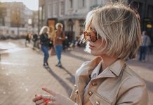 A blonde with a bob haircut walks through the city in the wind