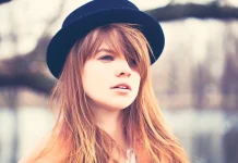 A red-haired girl with bangs under a hat