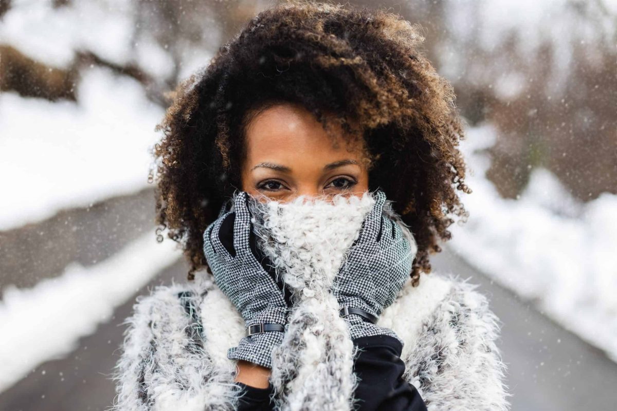 African woman with curly hair wrapped in a scarf in cold weather and snow African woman with curly hair wrapped in a scarf in cold weather and snow