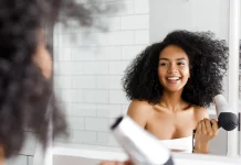 Black curly girl blow drying hair