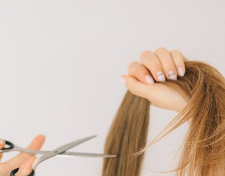 Remove a Hair Color Close-up of scissors cutting long hair indoors, highlighting hairstyling process.